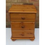 A pine bedside cabinet with three drawers.