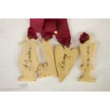 A 19th century scarlet ribbon of bone carved charms, each with inked inscriptions.