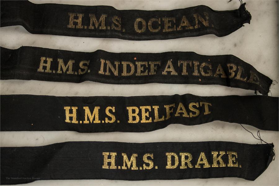 A group of Navy ribbons embroidered in gold thread; HMS Indefatigable, HMS Ocean, HMS Belfast, HMS