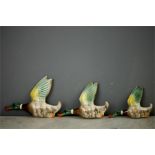 A set of three ceramic flying ducks of graduated size, together with a Capodimonte style figure