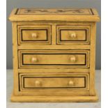 A miniature painted chest of drawers, two short over two long drawers, the top with foliate scroll