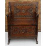 An oak carved monks bench/chair, the box seat havi