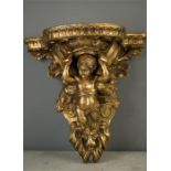A carved giltwood cherub corbel, the winged cherub between two scrolls above a lion head.
