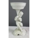 A white ceramic figure of a cherub raising a dish.