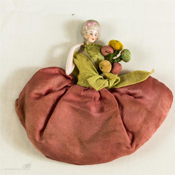 A Victorian porcelain doll top pin cushion.