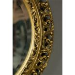 An oval wall mirror with pierced decorative gilt border.