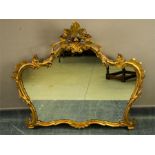 A giltwood Rococo style carved wall mirror, with crested top and scrollwork border.