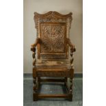 A 17th century oak wainscot armchair, the scroll carved top rail above a panel depicting a flowering