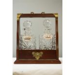 A mahogany tantalus containing three cut glass decanters each bearing silver bottle tags, with key.