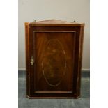 A small Edwardian mahogany corner cupboard, inlaid with chevron banding.