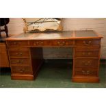 A late 20th century yew wood pedestal desk with three part green leather skivver above four