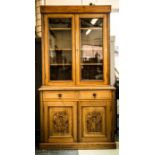 An Edwardian oak bookcase with glazed doors enclosing three shelves, the lower section having two