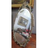 A silver-gilt oval table mirror with crested top and carved decoration.