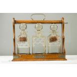 An oak tantalus, three cut glass decanters with two bearing name tags.