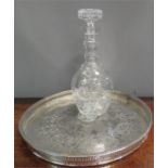 A circular silver plated tray together with a cut glass decanter.