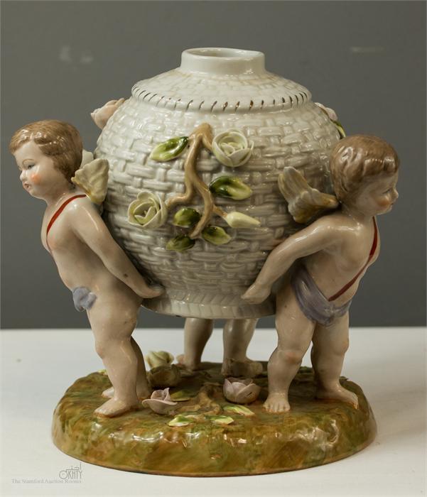 A 20th century Dresden jar with three putti raising the central basket, 18cm high.