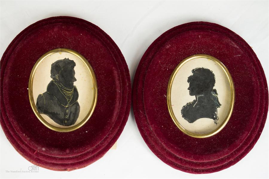 A pair of 19th century oval red velvet frames with handpainted silhouettes.