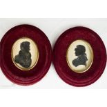 A pair of 19th century oval red velvet frames with handpainted silhouettes.