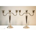 A pair of silver candleabra, each with three candle sockets, tapered stems and raised circular