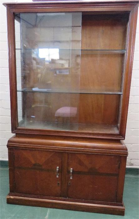 A 1950s glass display cabinet with sliding glass panel doors and two glass interior shelves, the