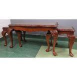 A nest of three mahogany tables with carved cabriole legs and glass tops.