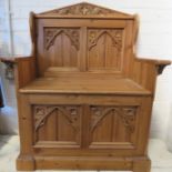 A pine carved child's settle, with the back panel carved with Gothic style arches.