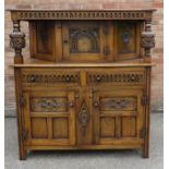 A reproduction oak court cupboard with baluster supports and canted top section.