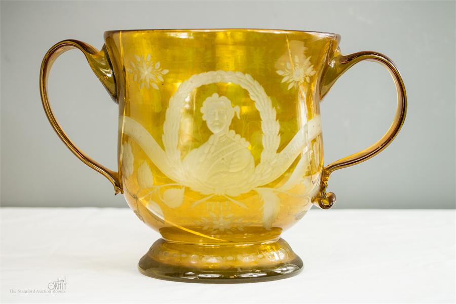 An 18th century yellow glass twin handled bowl, dated 1745 and engraved with portrait of Bonnie