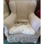 A wing back upholstered armchair with loose cover.