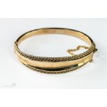 A 9ct gold bangle with a safety chain, 15.4g.