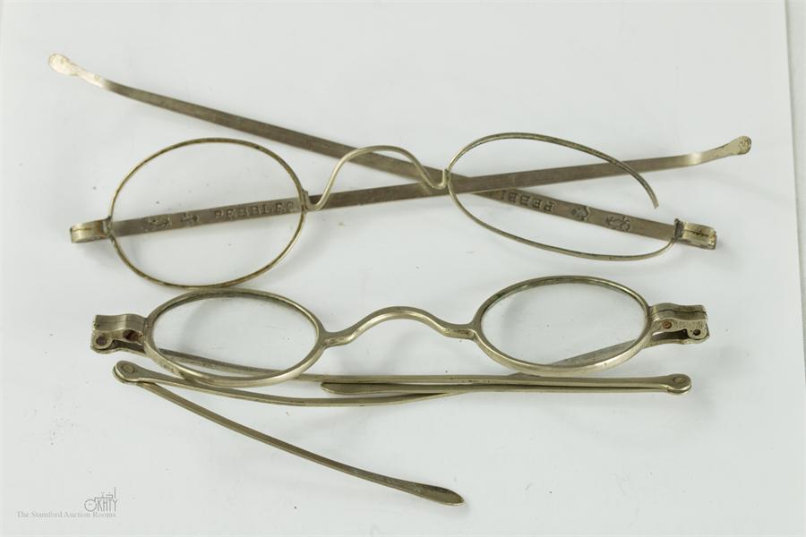 Two pairs of 19th century silver spectacles, one marked pebbles, the other with mod folding arms,