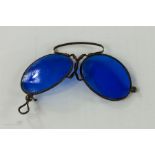 A pair of early 20th century steel folding blue lens sunglasses, in red leather case.