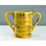 An early 19th century slipware twin handled mug, 'Happiness Lies in Imagination Not in Possession,