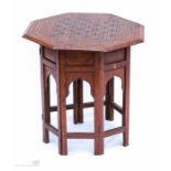 A middle eastern fruitwood table with octagonal top and folding base, inlaid with decoration.