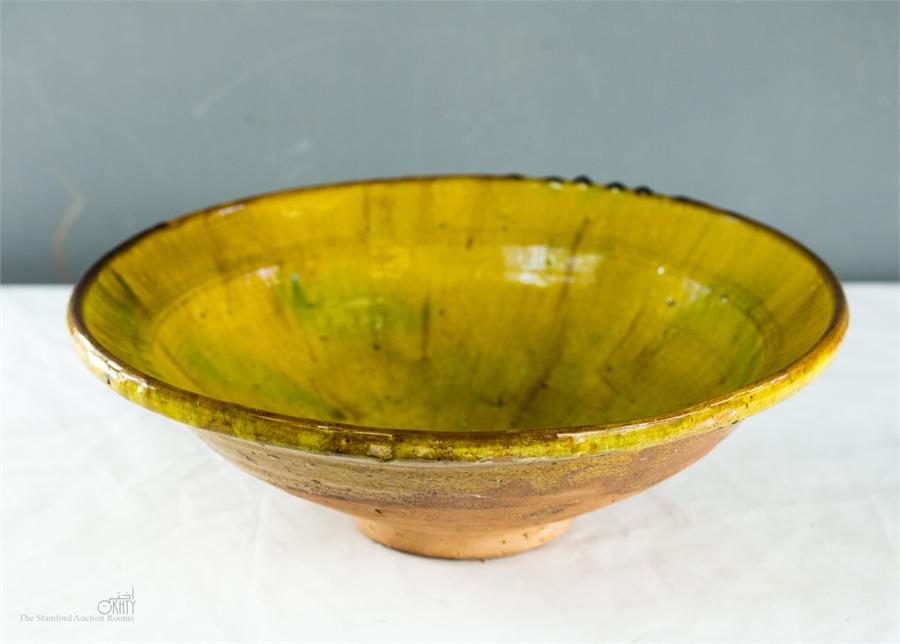 A glazed stoneware bowl, yellow glaze.