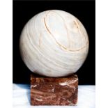 A marble sphere on red marble base, 34cm high.