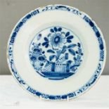 An 18th century blue and white delft plate depicting flowers to the centre.