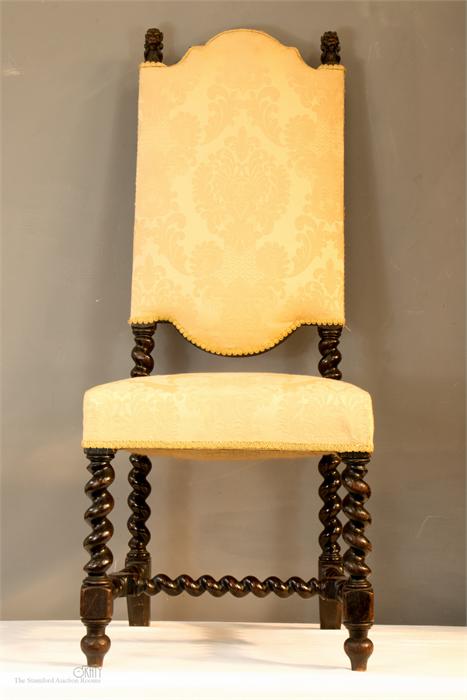An 18th century Spanish walnut high back chair, with two lion head carved finials, the shaped back