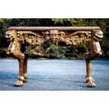 A Baroque style giltwood console table, carved with faces masks, swags and foliage. 84cm high, 131