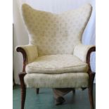 A 19th century mahogany carved wingback armchair, upholstered in cream with outswept back, and