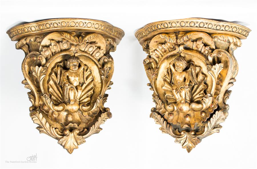 A pair of carved giltwood wall brackets, with cherubs to the centre.