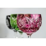 Three bohemian cut glass wine glasses in pink, red and green.