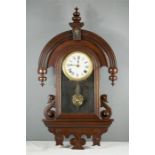 A mahogany wall clock, with Roman numeral dial, the arched case with turned finials.