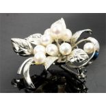 A silver and cultured pearl brooch fashioned as a spray of flowers set with nine pearls.