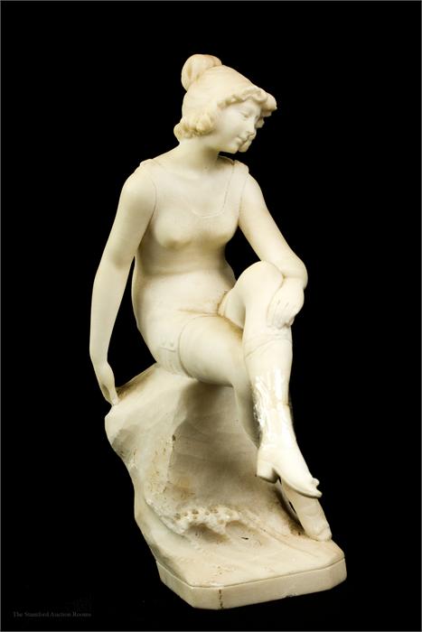 A marble carved figure of a seated woman.