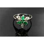 A 14ct white gold and emerald and diamond flower head ring.