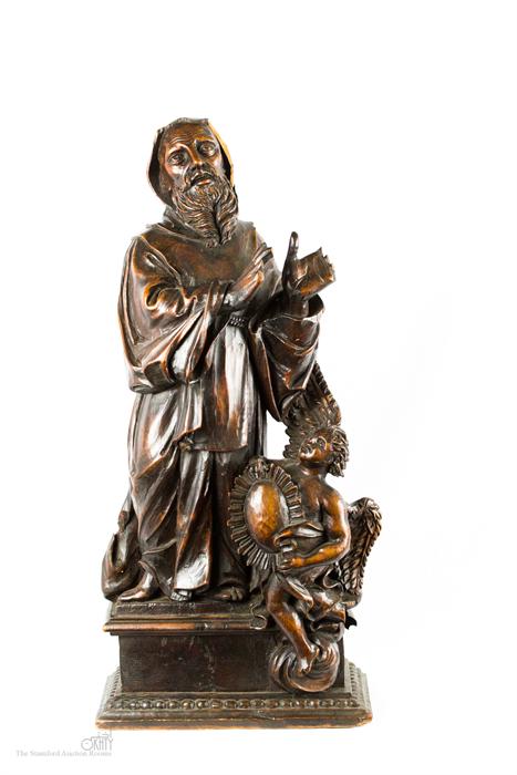 A 17th century carved sculpture of a Saint raised on a plinth.