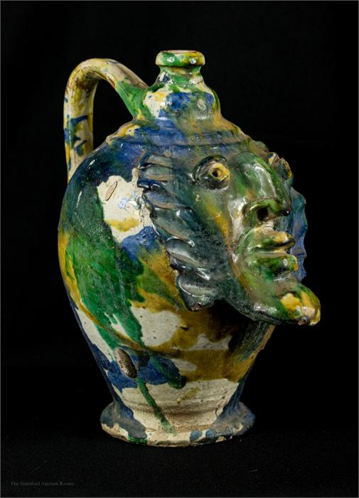 An early stoneware jar, yellow, green and blue slip glazed, modelled with a face mask. - Image 2 of 2