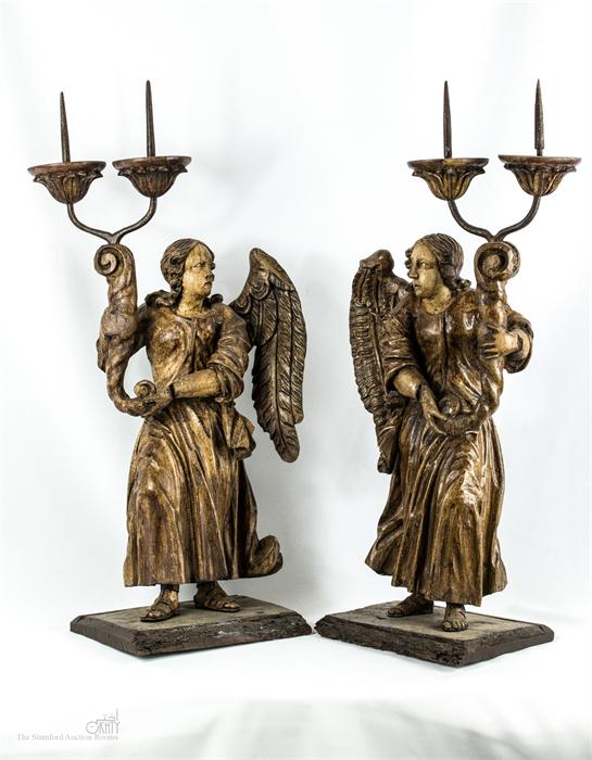 A pair of carved candlesticks, in the form of angels holding cornucopia, 58 by 28cm.