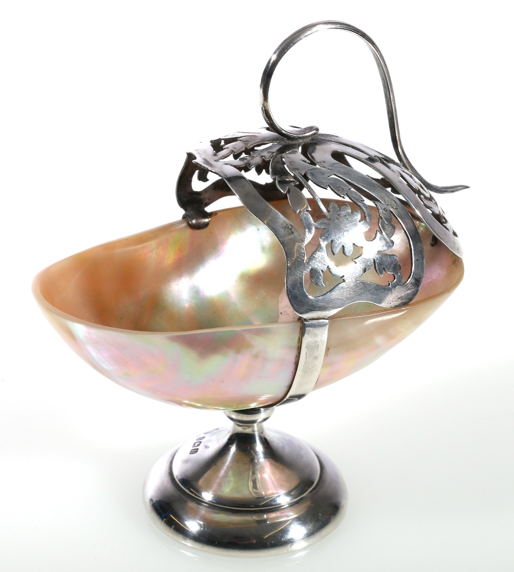 Silver mounted mother-of-pearl table salt, the pierced basket support with scroll handle,